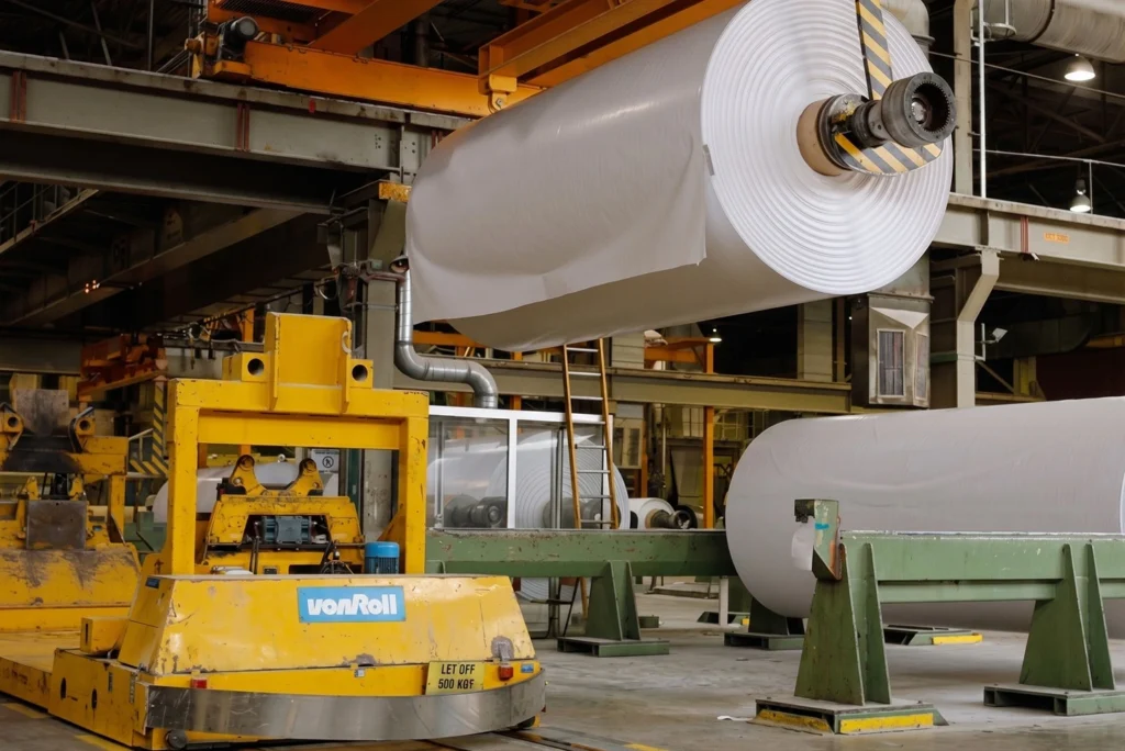 Overhead Crane Lifting a Large Paper Roll in a Manufacturing Facility
